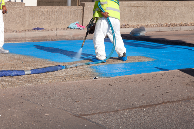 Worker applying flooring system with a spray machine